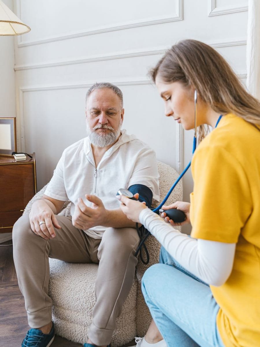 A healthcare professional checking on an elderly man at home